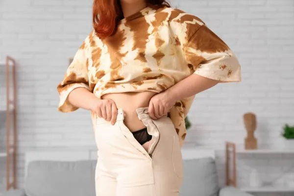 Image of woman trying to do her trousers up after pregnancy weight gain Sandwich