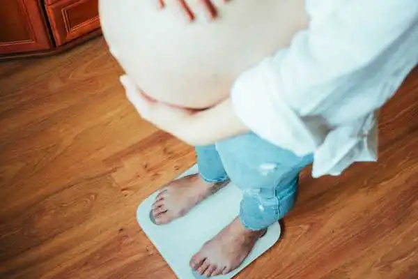 Image of woman weighing herself and experiencing weight gain through pregnancy Sandwich